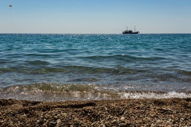 Uzaklarda yelken açan bir gemi manzaralı deniz kıyısı..