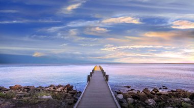 Long narrow pier protruding out into Chesapeake Bay at sunset under a beautiful sky clipart