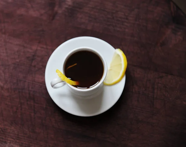 Espresso romano coffee with lemon in a white cup on a dark wooden rustic table top view