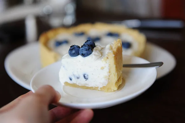 Piece Cheesecake Blueberries White Plate Hand Focus Background Whole Cheesecake — Stock Photo, Image