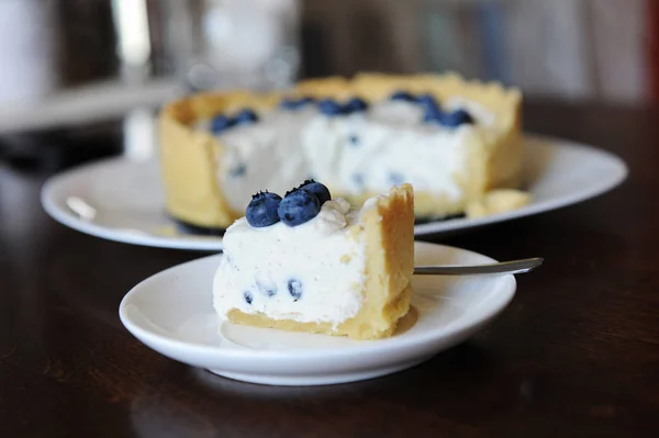 Pedaço Cheesecake Com Mirtilos Placa Branca Foco Fundo Cheesecake Inteiro — Fotografia de Stock