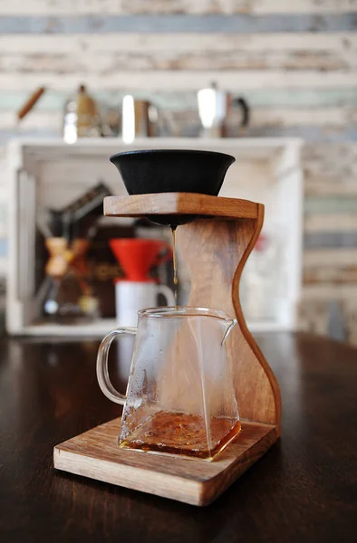 Making coffee in the black paperless porous ceramic porcelain filter on wooden coffee station. Devices for brewing in the background