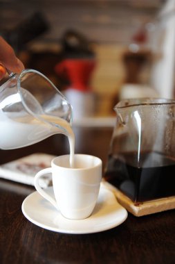 Hindistan cevizi sütü sade kahve bir fincan içine dökülür. Aygıtları el ile kahve arka planda bira için