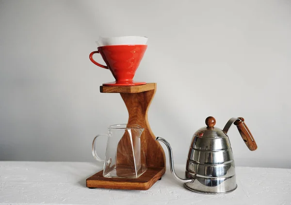 Coffee brewing in red purover on wooden coffee station. Glass serving jug. Kettle gooseneck. White background. Free space for design