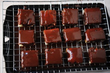 Tatlı lamington tepsi ızgara ile pişirme üzerinde çikolata sosu ile. Taze pişmiş