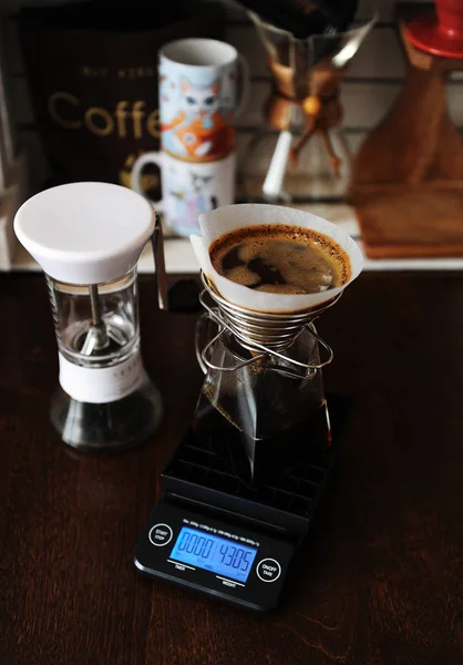 Alternative manual coffee brewing with paper filter in stainless steel spring dripper. On the electronic scale. Manual coffee grinder