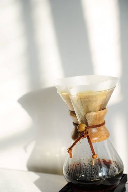 Kağıt damlatıcı filtre ile bira alternatif el ile kahve. Beyaz duvar üzerinde güneş gölgeler