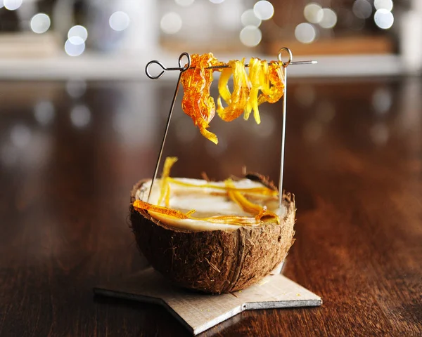 Creative serving of cappuccino in a coconut with hanging caramel. Food coffee styling