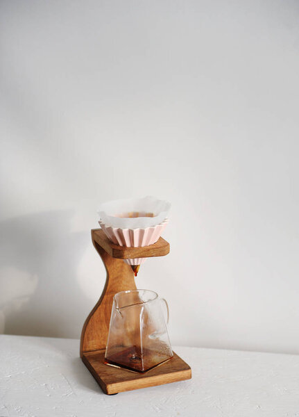Деревянный кофе капельница стоять на белом фоне. Свободное пространство для дизайна. Розовая керамическая капельница с бумажным фильтром
