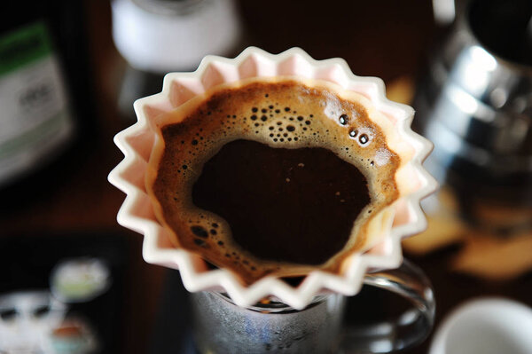 Альтернативная ручная ручная варка кофе в розовой керамической дриппер оригами с бумажным фильтром. Закрыть, вид сверху
