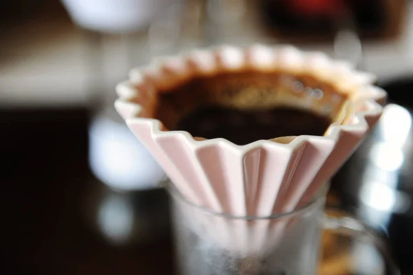 Альтернативная ручная ручная варка кофе в розовой керамической дриппер оригами с бумажным фильтром. Закрыть — стоковое фото