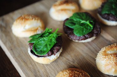 Burger ıspanak Yeşiller, pirzola, berry sos ve susam çörek. Pişirme işlemi. Düzen bir ahşap tahta üzerinde