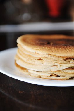 Bir yığın krep koyu ahşap bir masa üzerinde beyaz bir plaka üzerinde