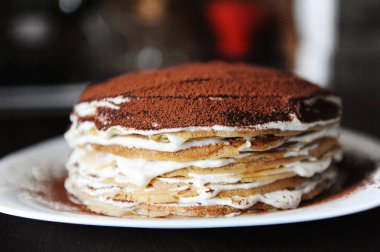 Krep pasta doldurma tiramisu ile toz kakao ile silkeledi. Beyaz tabak, kahve evin arka plan. Yan görünüm, portre
