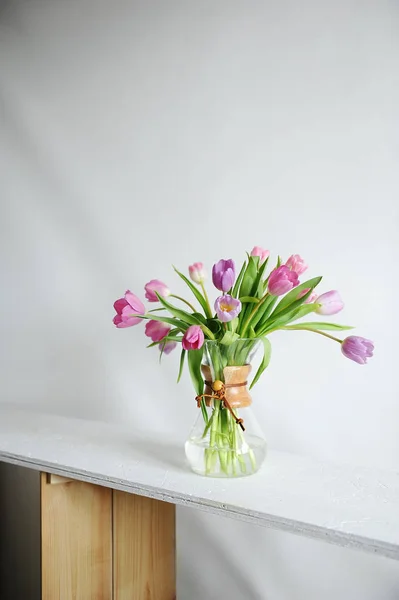 Bukiet tulipanów w karafki dzbanek kawy na biały stół w promieniach słońca. Na białym tle. Pąki różowy i fioletowy — Zdjęcie stockowe