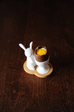 Paskalya tatlı çikolata yumurta beyaz ve sarısı taklit krema ile. Bunny ile sahibi. Ahşap arka plan, boş alan