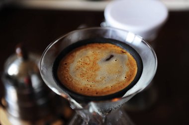 Alternatif el ile kahve siyah gözenekli japonic seramik kağıtsız damlatıcı filtrede bira. Cam sürahi. Closeup Üstten Görünüm