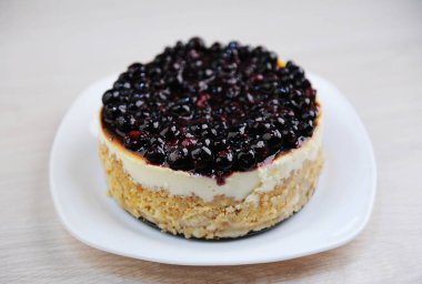 Whole blueberry cheesecake on a white plate