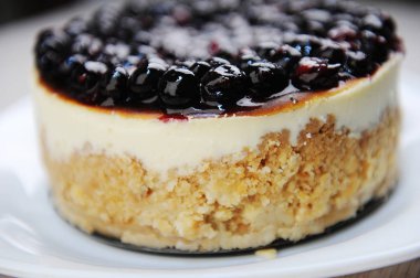 Whole blueberry cheesecake on a white plate side view