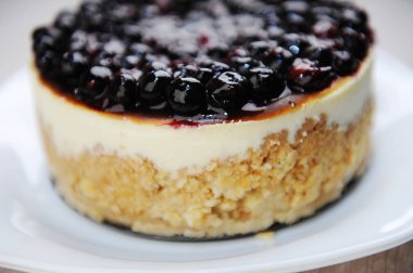 Whole blueberry cheesecake on a white plate side view