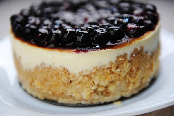 Whole blueberry cheesecake on a white plate side view