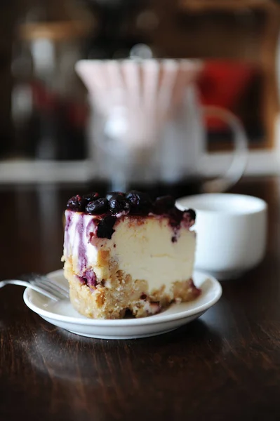 Pedaço de cheesecake de mirtilo em uma vista lateral placa branca. Café em origami gotejador. Deliciosa sobremesa — Fotografia de Stock