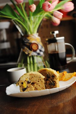 Beyaz tabakta şekerlenmiş meyve ve lezzet ile Muffins kek. Fransız basın kahvesi. Dekantörde pembe laleler