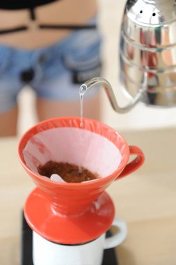 Kız barista kahve damlama yöntemi demler. Kırmızı hario v60 huni içine kaz boyun su ısıtıcısı su dökme.
