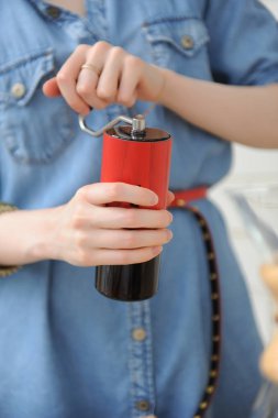 Kadın elinde kırmızı manuel öğütücü closeup. Barista kahve demlemek