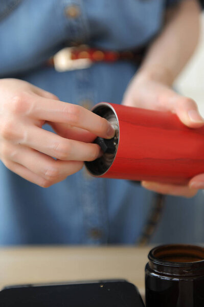 Бариста устанавливает степень измельчения на красной ручной мельнице крупным планом
