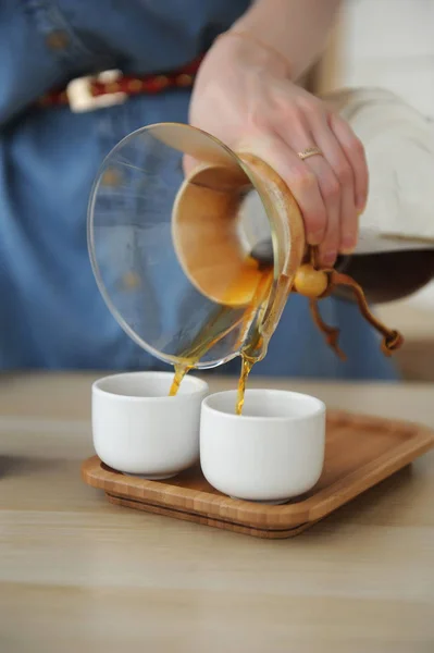 Выливать кофе из химикатов в две белые чашки одновременно — стоковое фото