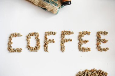 Beyaz arka planda kahve şeklinde yeşil kahve çekirdekleri.