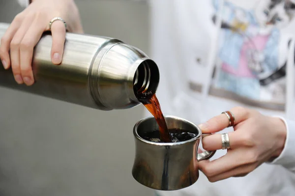 Кофе в пути. Девушка наливает горячий черный кофе из термоса на открытом воздухе. Закрыть — стоковое фото