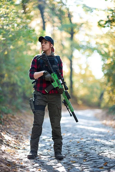 Female hunter with rifle on stone road in the forest