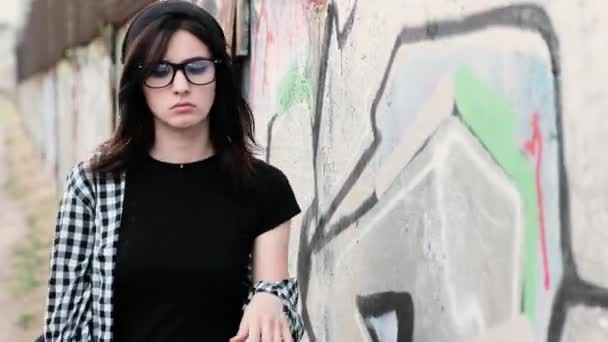 Een triest offfended meisje kijkt grillige tijdens het wandelen en leunend tegen de muur — Stockvideo