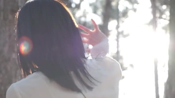 Une jeune belle femme regarde le soleil à travers les doigts dans les bois. Vue de l'arrière — Video