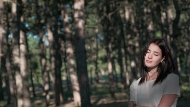 Eine junge schöne Frau genießt die Wärme und Helligkeit des Sonnenlichts und berührt sanft ihr Haar — Stockvideo