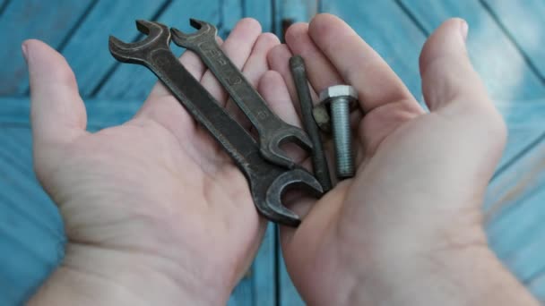 As mãos de um homem despejam várias ferramentas em um fundo de madeira azul — Vídeo de Stock