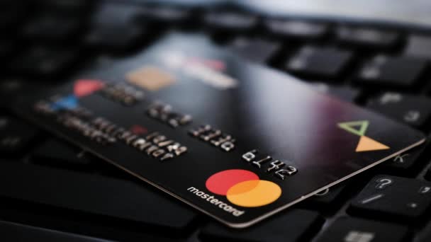 Bankovní karta Visa... Světla z obrazovky spadají dvakrát na kreditní kartu, která leží na klávesnici — Stock video