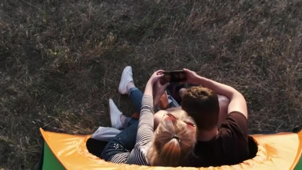 A view of a couple making selfie in a tent and then their sihlhouette is seen through the back of a tent — Stock Video