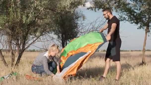 Ein Paar stellt ein Zelt auf den Boden — Stockvideo