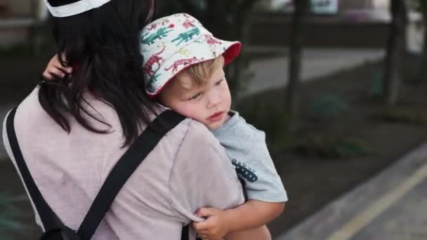 Kochająca matka niesie ze sobą swoje dziecko zmęczony i znudzony, klepiąc go przychylnie — Wideo stockowe