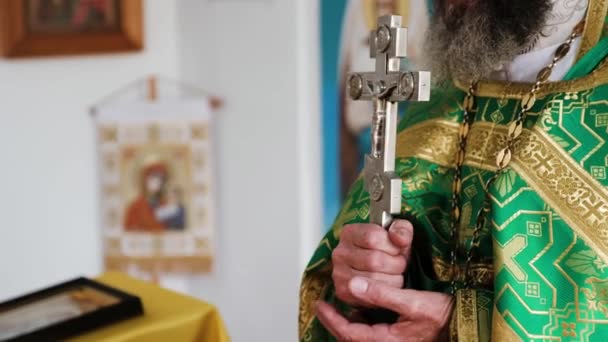 Blick auf ein Kreuz in den Händen eines Priesters, der das Gebet spricht — Stockvideo