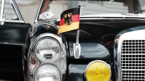 Людина з представником роду закрили двері ретро автомобіля. Чорний авто 70s німецького виробництва. Прапор Німеччини фіксується на автомобіль. — стокове відео