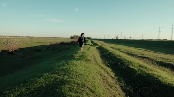 秋天阳光明媚的日子, 带着帽子的快乐女孩赤脚奔跑在草原的中间. — 图库视频影像