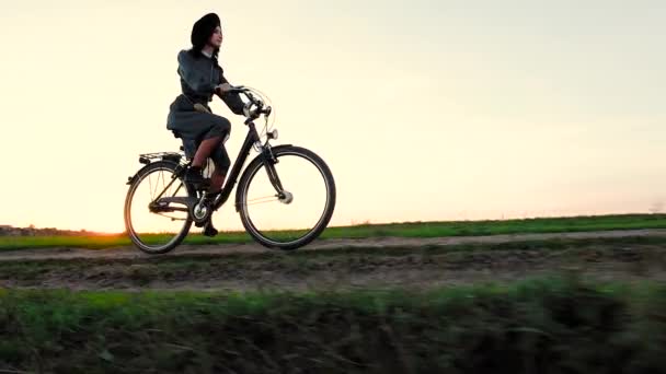 Молодая девушка в шляпе и с велосипедом в степи . — стоковое видео