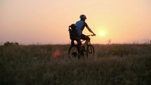 Le couple marié se déplace à vélo contre le soleil levant . — Video