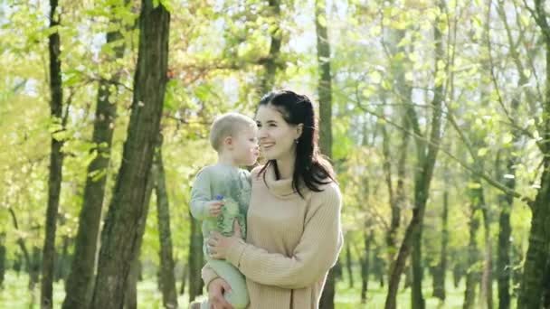 Счастливая женщина с сыном гуляет в осеннем парке — стоковое видео