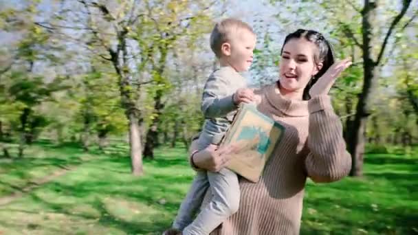 Молода мати зі своїм маленьким хлопчиком розважається в осінньому парку — стокове відео