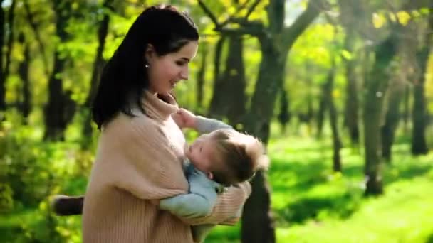 Joven madre con su pequeño bebé divirtiéndose en el parque de otoño — Vídeo de stock